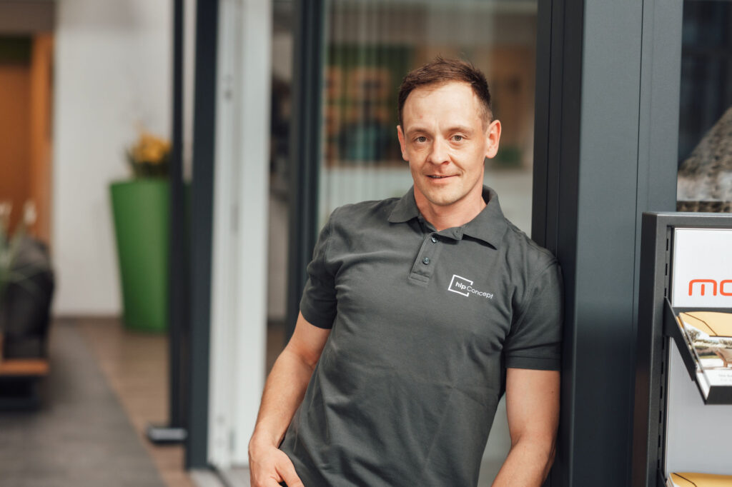 Ein junger Mann lächelt in die Kamera. Er ist Monteur des Unternehmens hip Concept